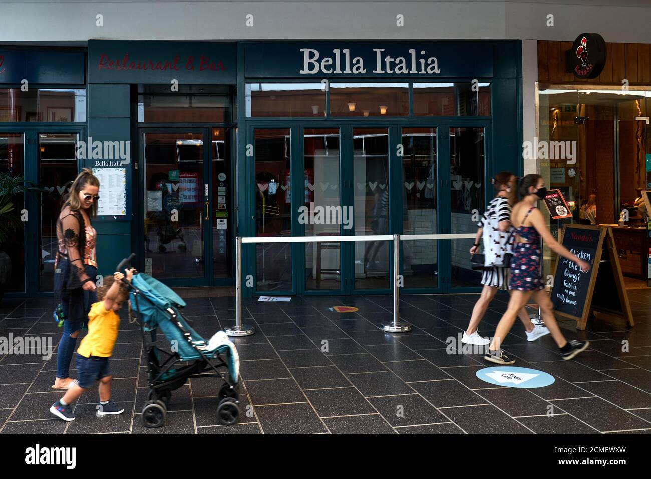 People walk past a closed Bella Italia restaurant in the Atrium shopping centre in Camberley town centre Stock Photo