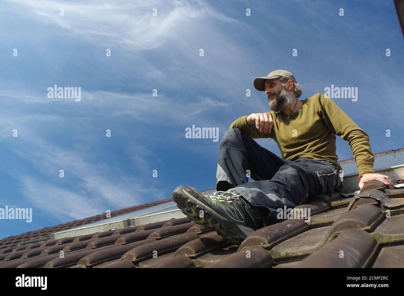 bearded roofer resting on top of a roof   sunny day Stock Photo