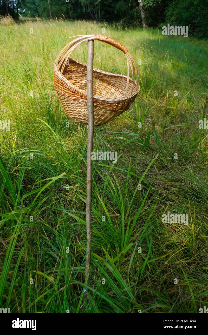 closeup picnic basket hanging on a rod in grass, outside with green