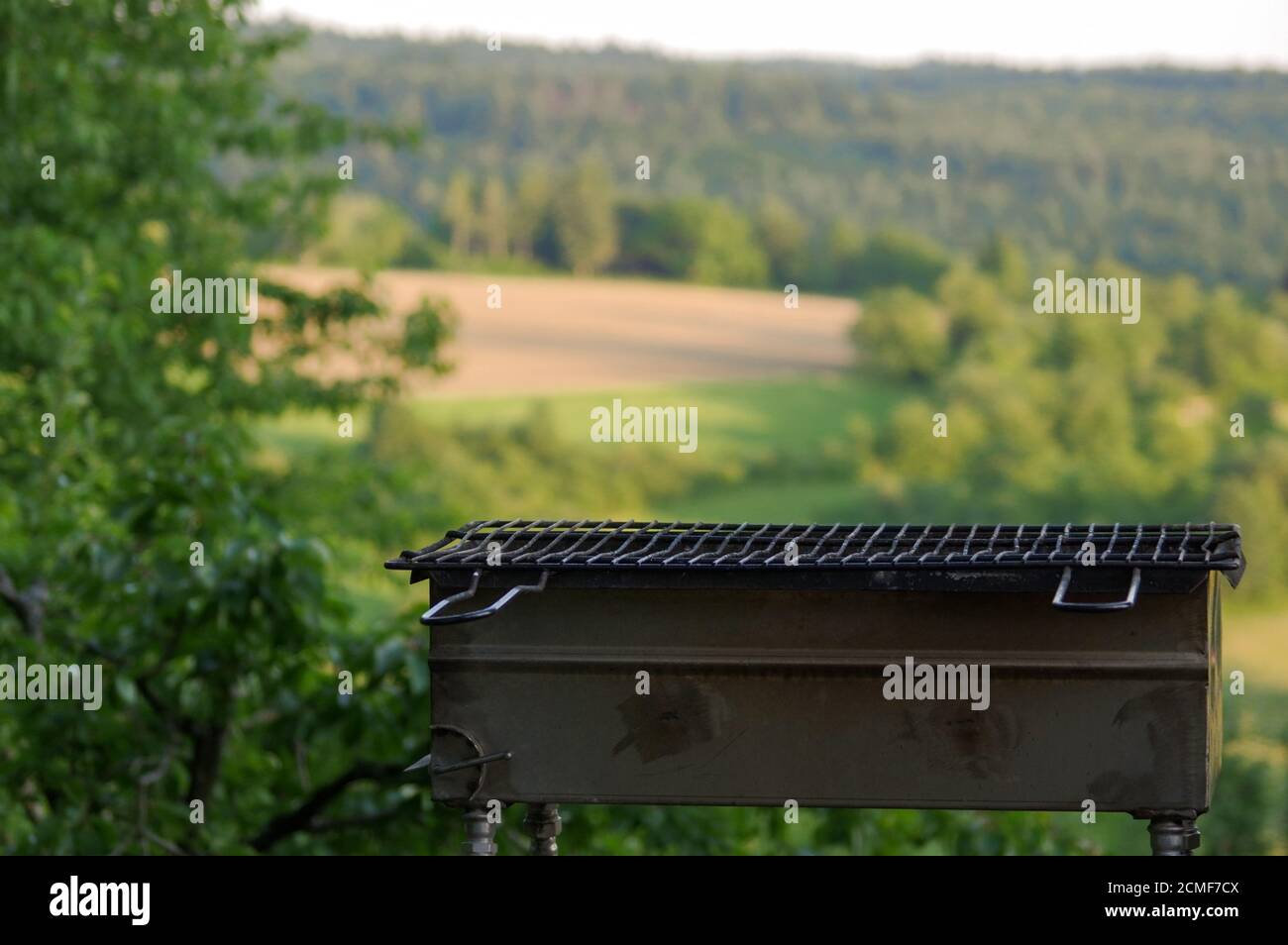Empty portable BBQ grill in front of a fresh green summer landscape Stock Photo