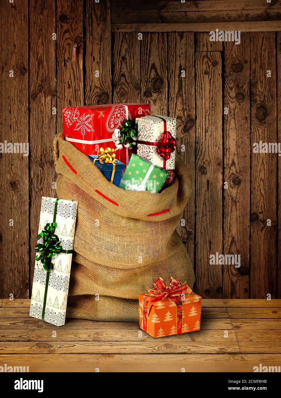 Santas present sack with gift boxes against old rough wooden plank wall Stock Photo