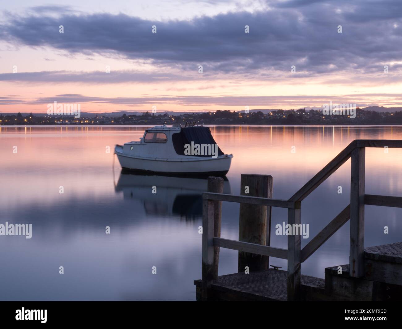 A boat reflects in the still water of the Tauranga harbour waters on a windless night Stock Photo