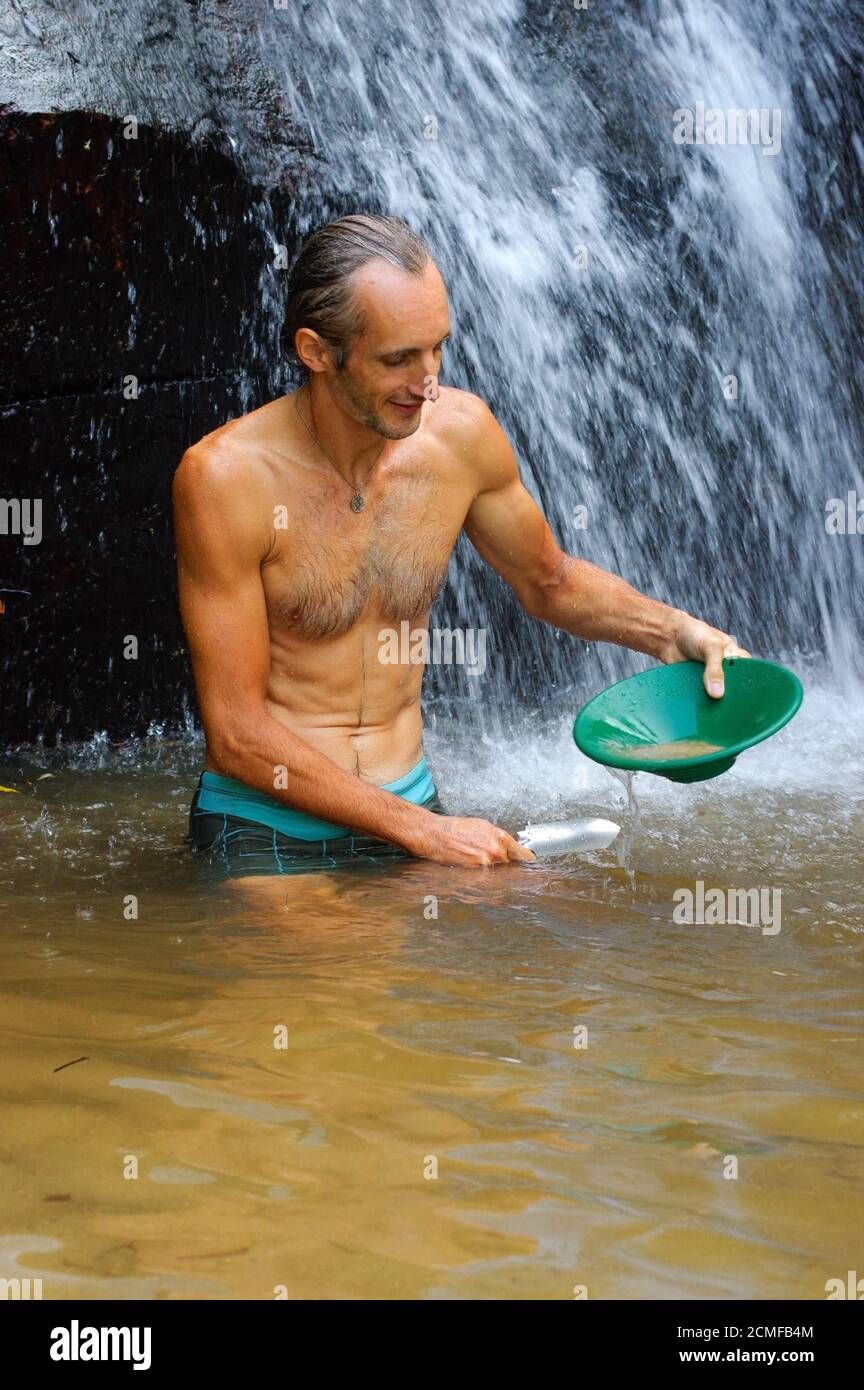 prospector panning gold in a river with sluice box with a waterfall in the background Stock Photo