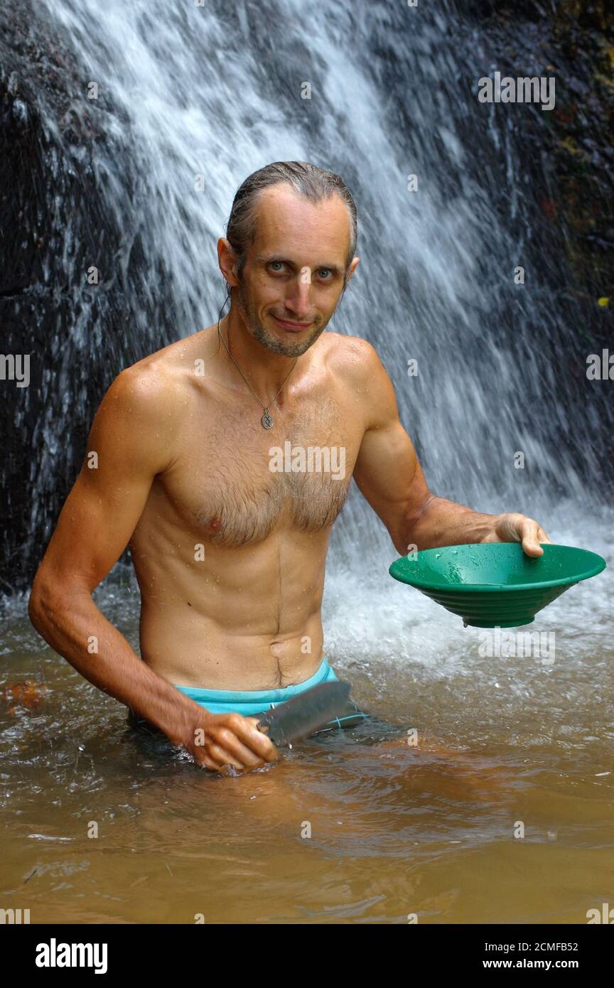 prospector panning gold in a river with sluice box waterfall in the background Stock Photo