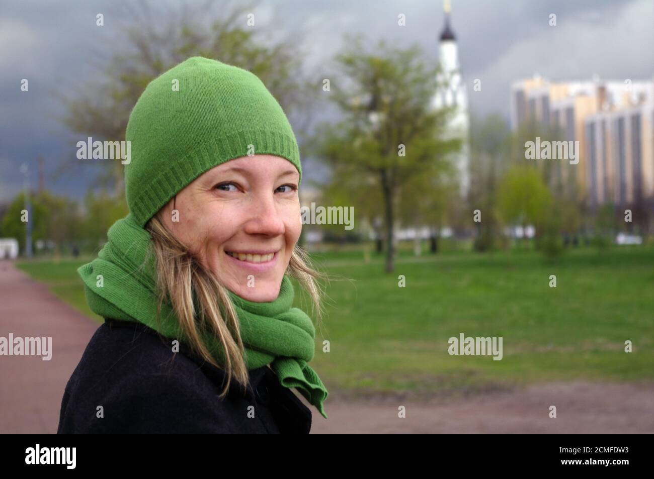 happy woman at a spring day walking on path to the church, close-up potrait Stock Photo