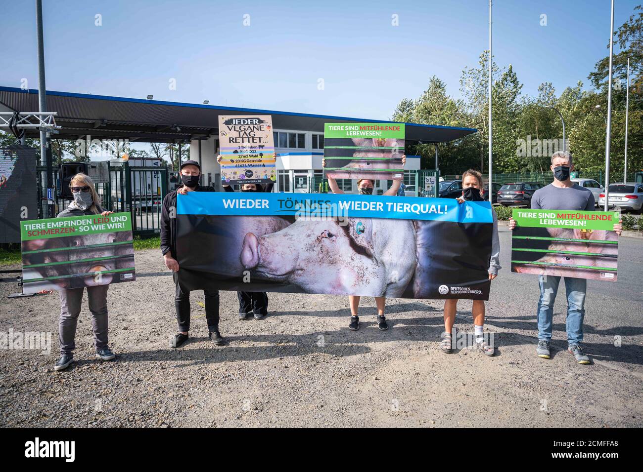 17 September 2020, Lower Saxony, Sögel: Animal welfare activists stand protest posters with the inscription 'Animals feel suffering and pain - just like us! (l and r) and 'Tönnies again - animal suffering again!' (M) in front of the premises of a slaughterhouse in Sögel after defects and infringements in a nearby pig fattening farm in the district of Emsland became known. According to the association 'Deutsches Tierschutzbüro', the company in Sögel is one of the main purchasers of pigs from the fattening farm in question and is part of the Tönnies group of companies. The Tönnies group defended Stock Photo