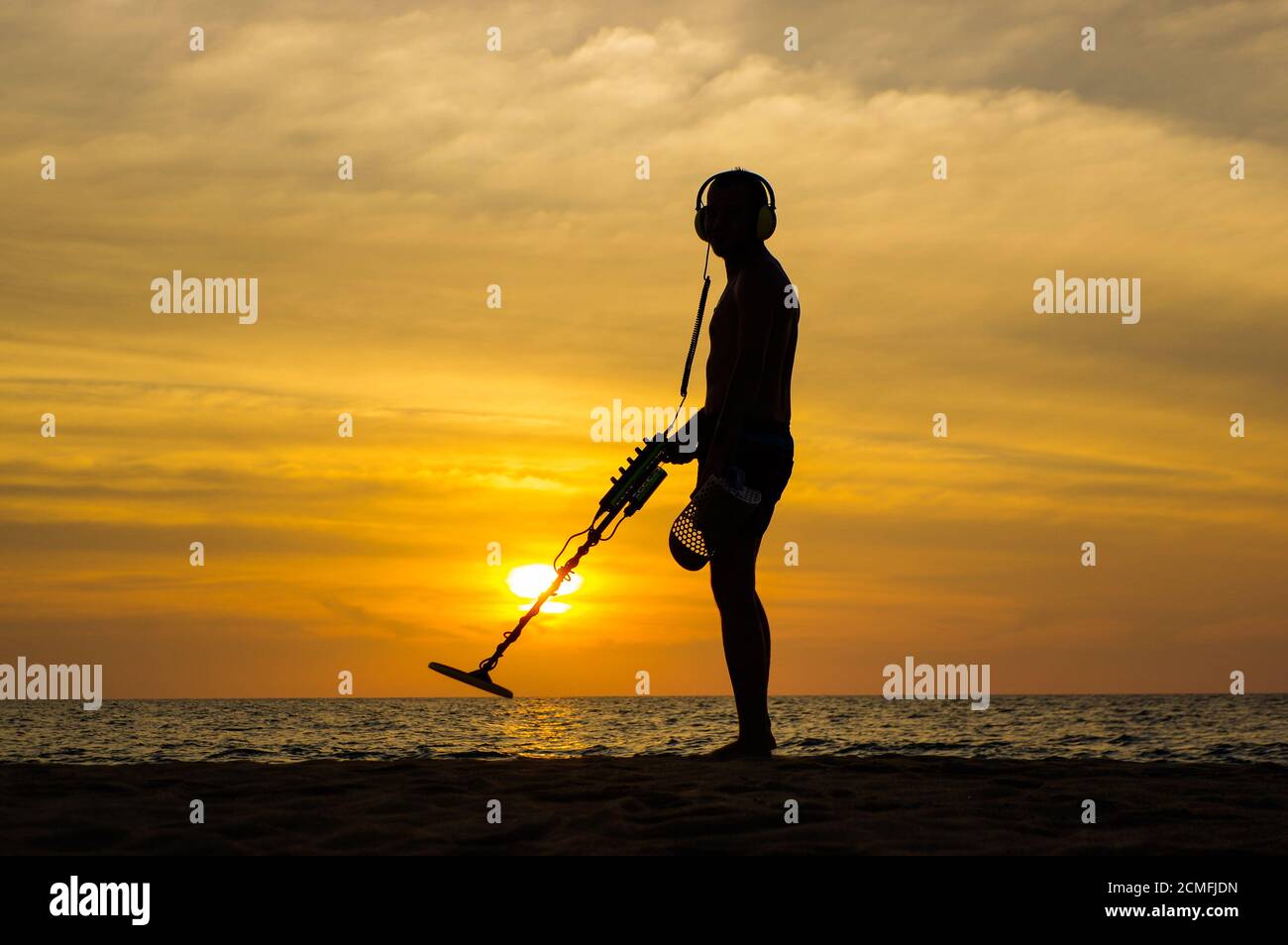 Treasure hunter with Metal detector on sunset the beach Stock Photo - Alamy