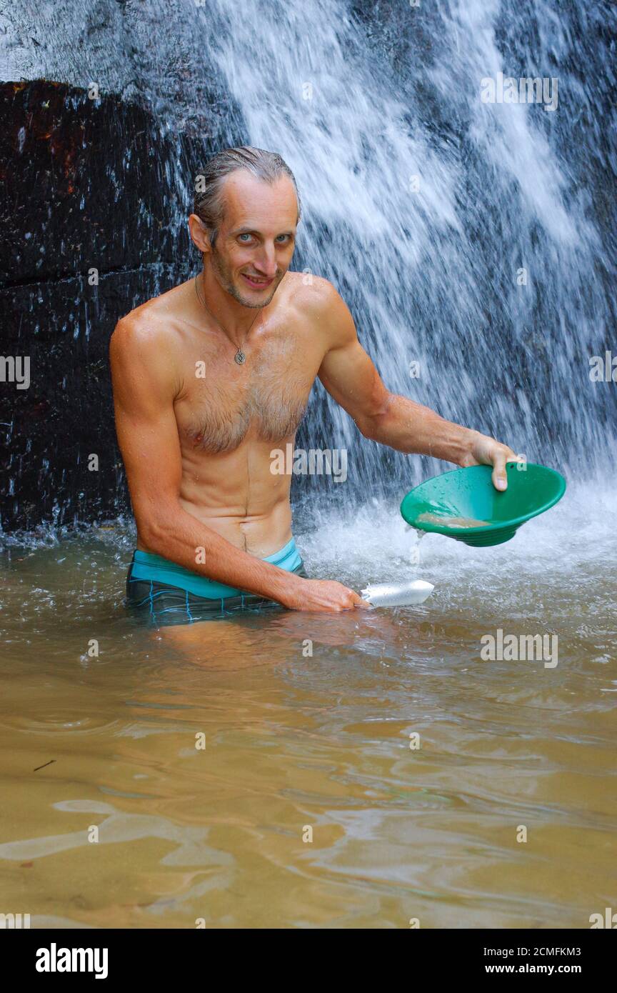 prospector panning gold in a river with sluice box on  waterfall Stock Photo