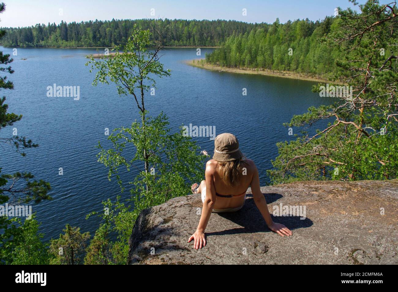woman enjoys views of the lake. A relax on the lakeshore with forest arround. Supervision over the h Stock Photo