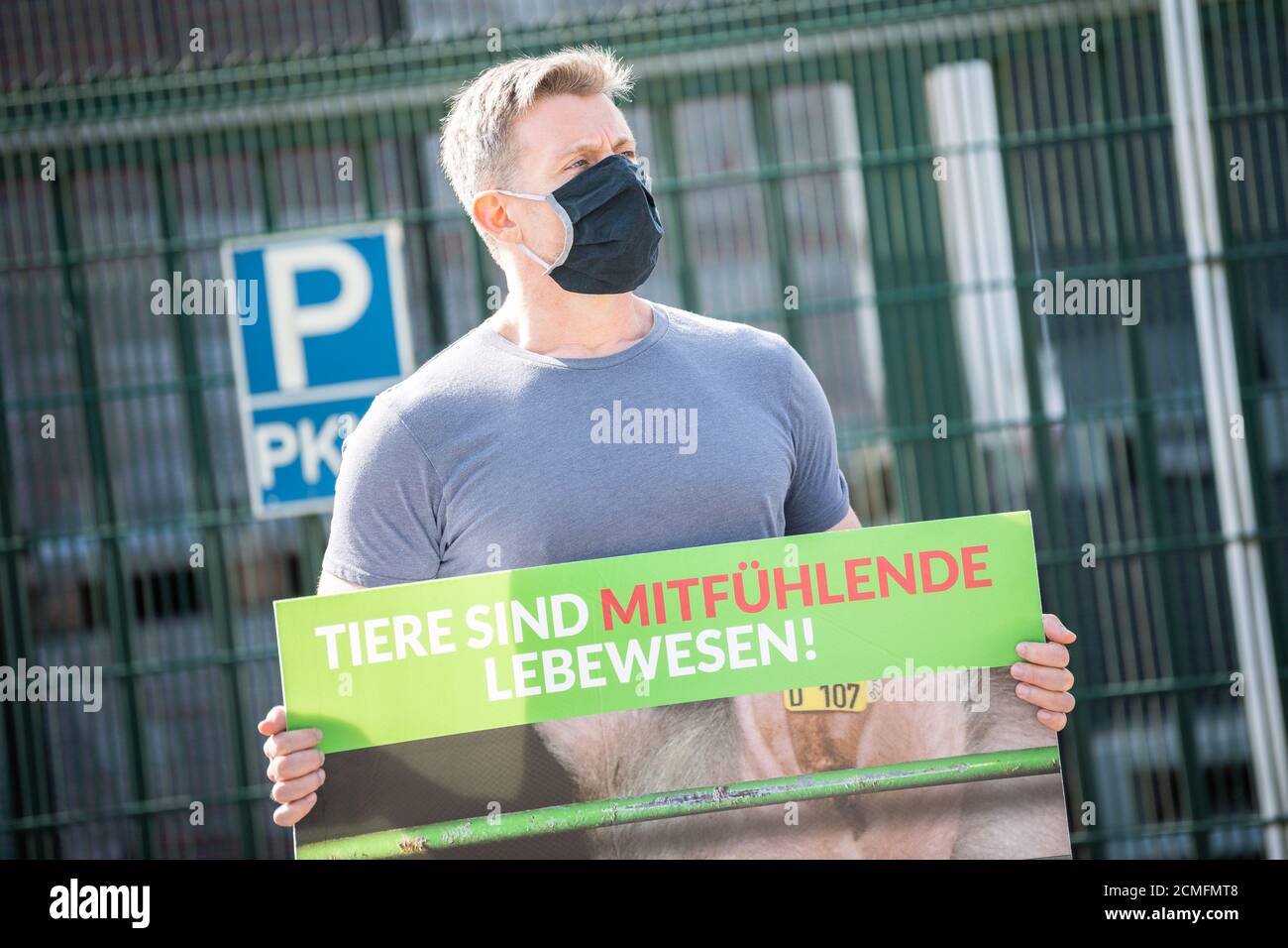 17 September 2020, Lower Saxony, Sögel: An animal protection activist stands with a protest sign saying 'Animals are compassionate living beings' in front of the premises of a slaughterhouse in Sögel after the discovery of deficiencies and violations in a nearby pig fattening farm in the Emsland district. According to the association 'Deutsches Tierschutzbüro', the company in Sögel is one of the main purchasers of pigs from the fattening farm in question and is part of the Tönnies group of companies. The Tönnies group defended itself against the accusations of the animal rights organization. P Stock Photo