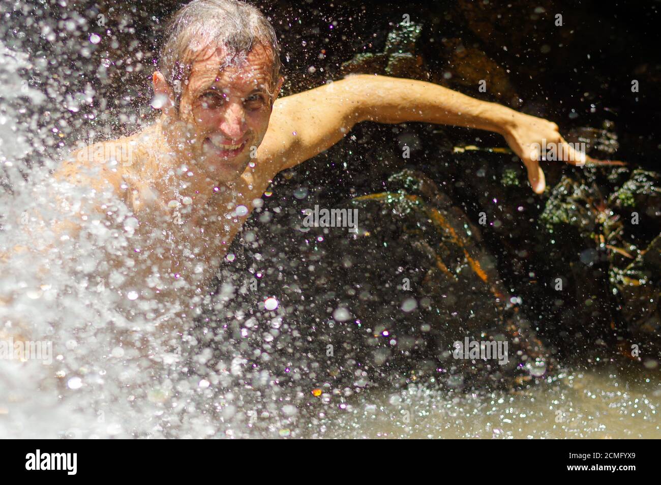 Man taking a relaxing shower under waterfall. outside Stock Photo Alamy