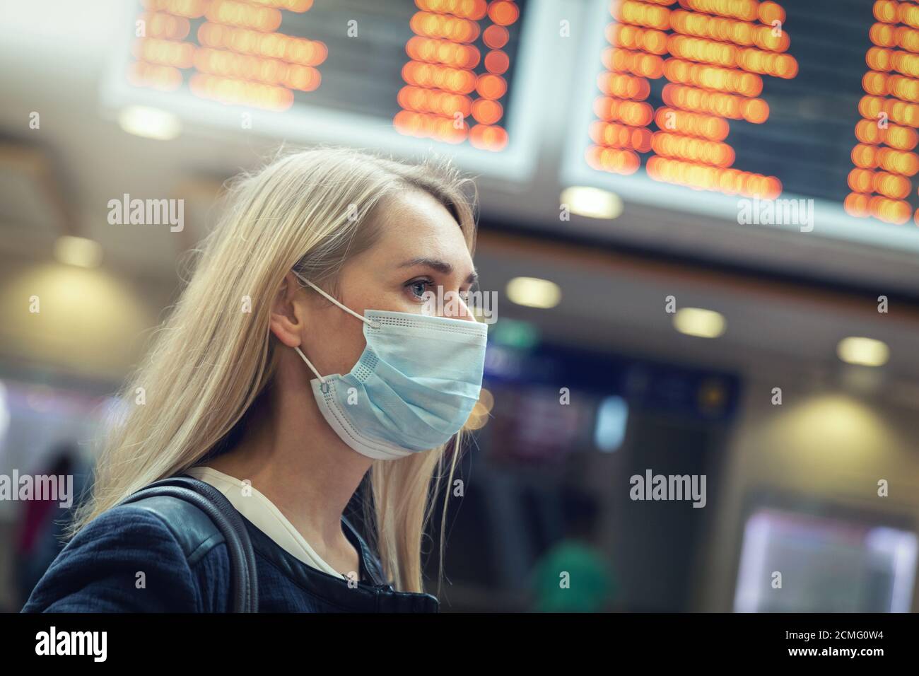 woman wearing protective face mask at crowded train station during virus pandemic Stock Photo