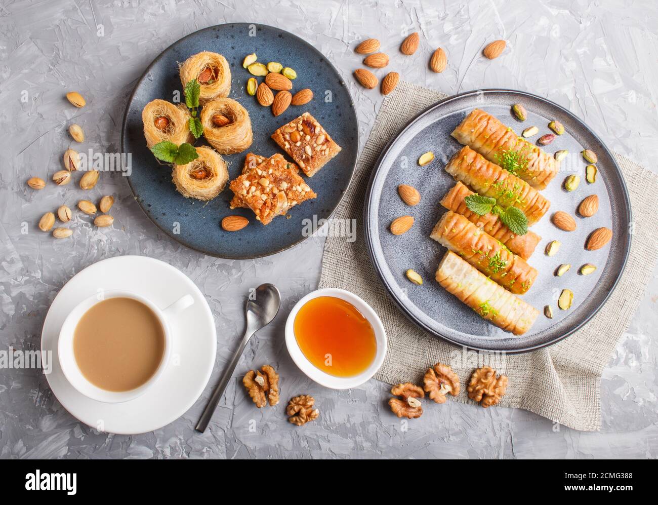Set of various traditional arabic sweets: baklava, kunafa, basbus in ceramic plates on a gray concrete background. top view, flat lay. Stock Photo