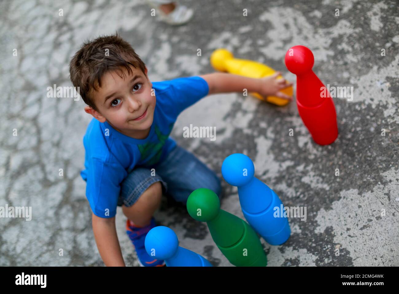 beautiful child plays in the garden with bowling pin amused after the end of covid 19 Stock Photo