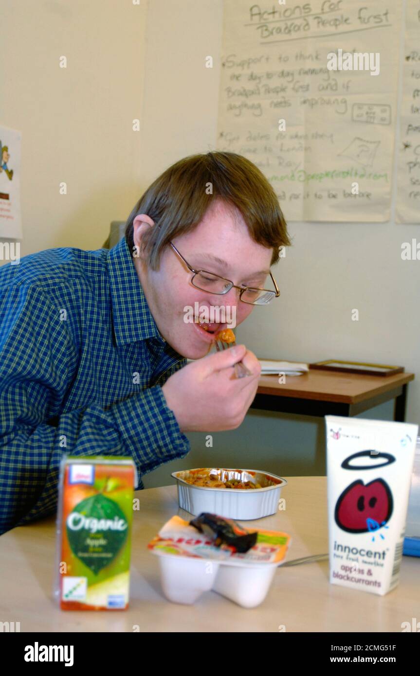 Man with learning disabilities eating lunch in community centre; Bradford Yorkshire UK Stock Photo