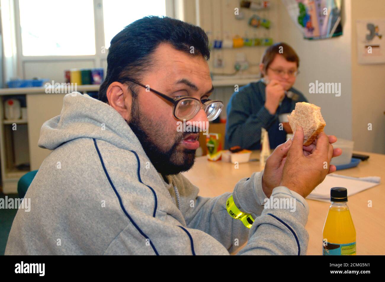 Man with learning disabilities eating lunch in community centre; Bradford Yorkshire UK Stock Photo