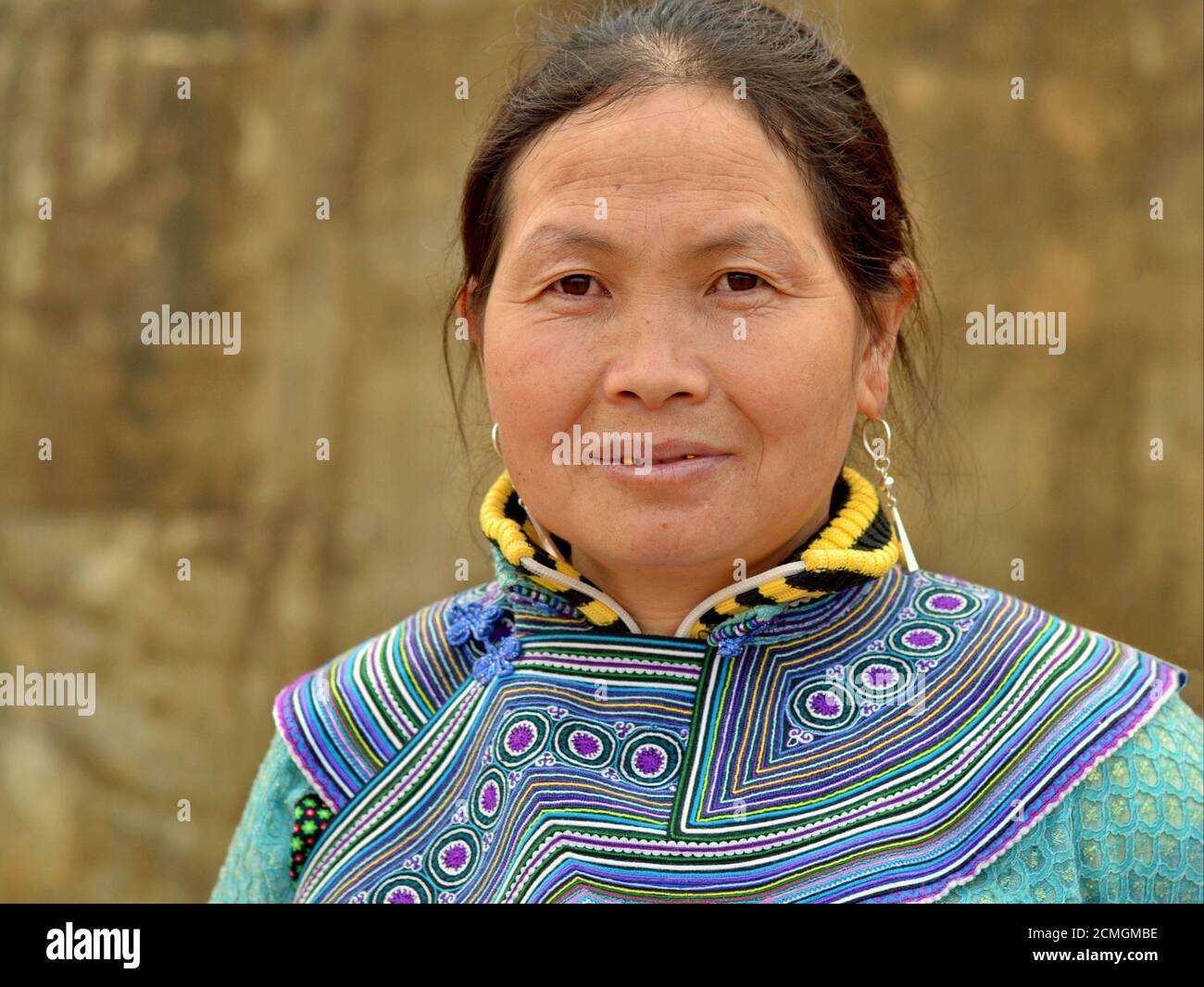 Middle-aged Vietnamese Flower Hmong hill-tribe woman wears embroidered traditional attire in blue and poses for the camera. Stock Photo