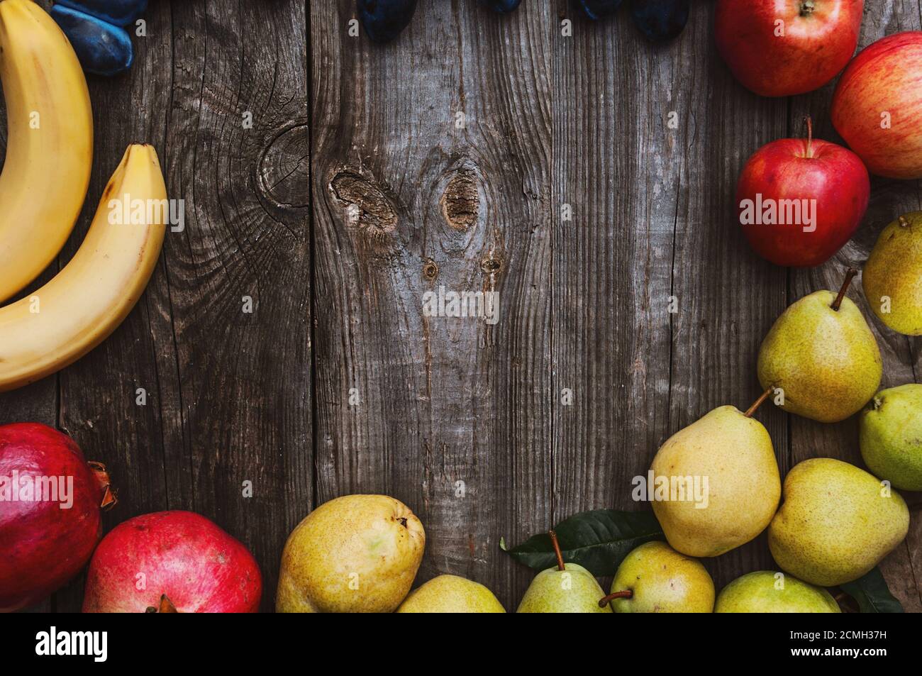 Fresh fruits on a gray wooden surface, bananas, apples, plums and pears Stock Photo