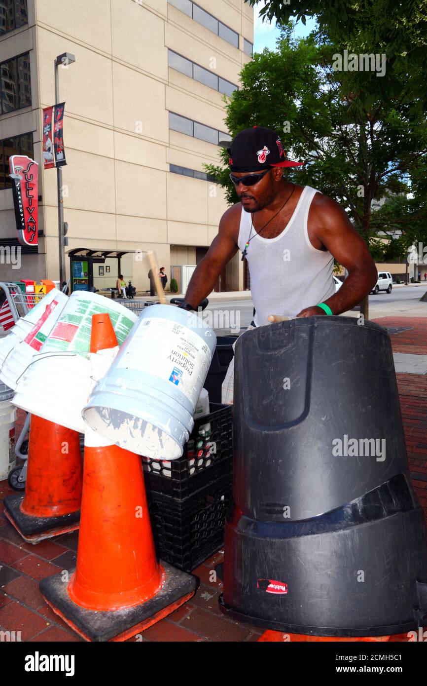 African American man playing homemade drum kit made from plastic buckets and bins in street, Baltimore, Maryland, USA Stock Photo