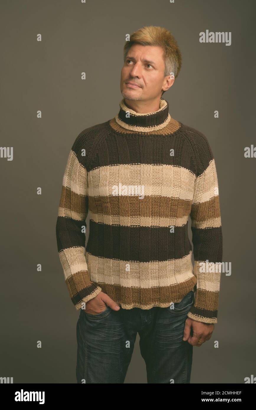Man With Blond Hair Wearing Turtleneck Sweater Against Gray Background man-with-blond-hair-wearing-turtleneck-sweater-against-gray-background
