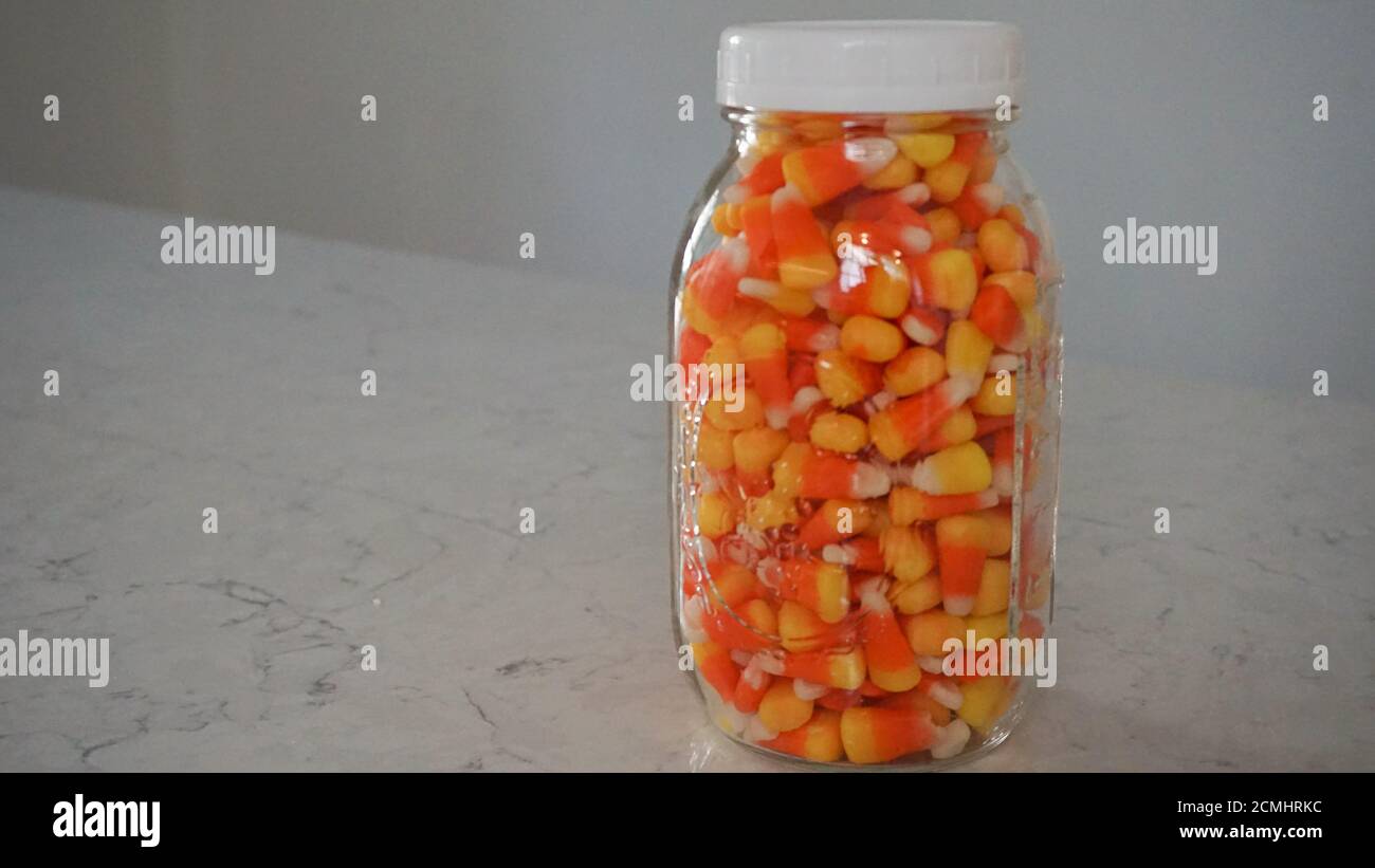 Glass mason jar filled with candy corn for Halloween. Guess the number of pieces inside. Stock Photo