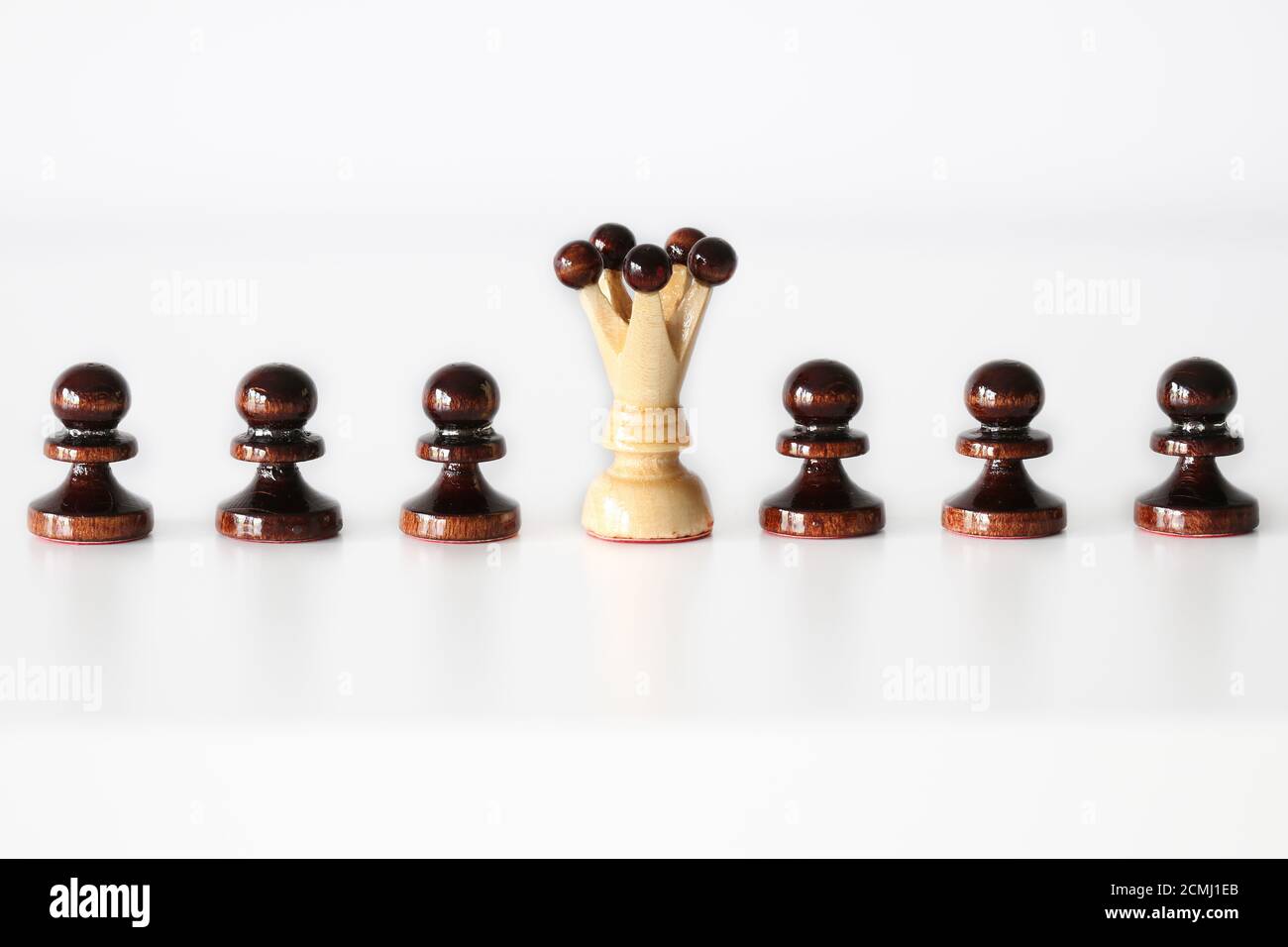 Row of black pawn chess pieces with white queen in the middle on white background - stand out of the crowd concept Stock Photo