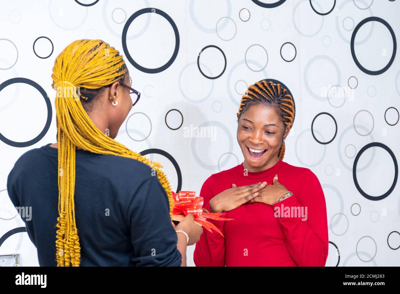 lady receiving a gift from a friend looking surprised Stock Photo