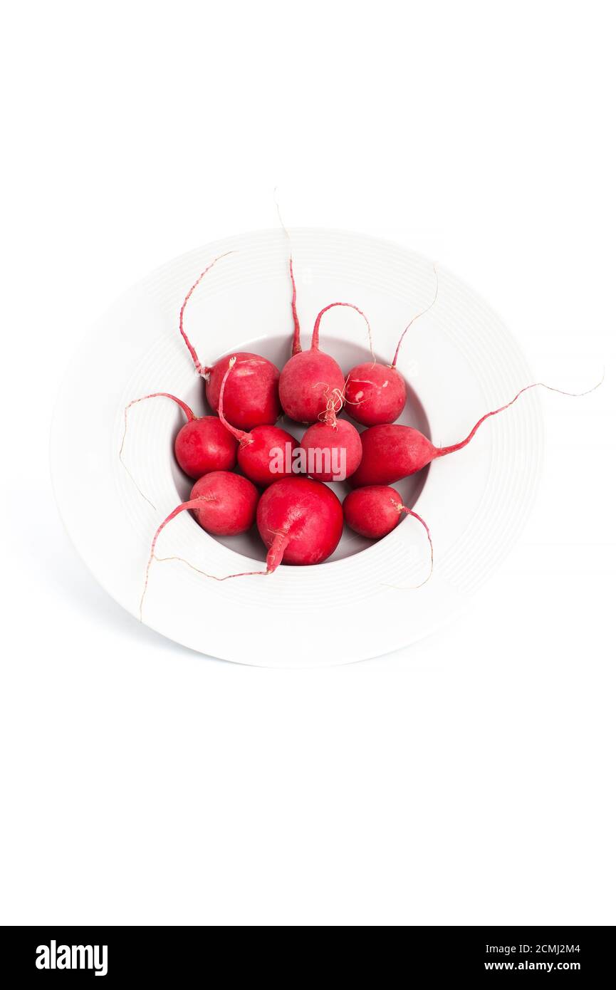 Fresh radishes in a round deep plate on a clean white background. Stock Photo