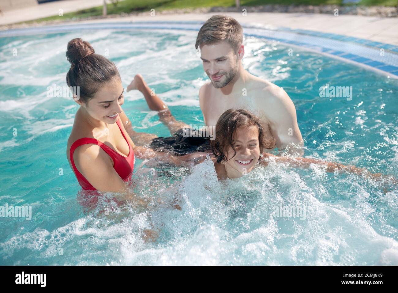 Kid In Pool With Parent Parents teaching their son to swim in the pool Stock Photo - Alamy