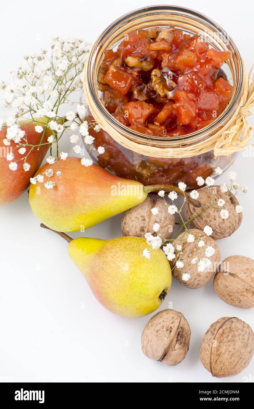 Pear jam with walnuts in a jar on a white background close-up. Stock Photo