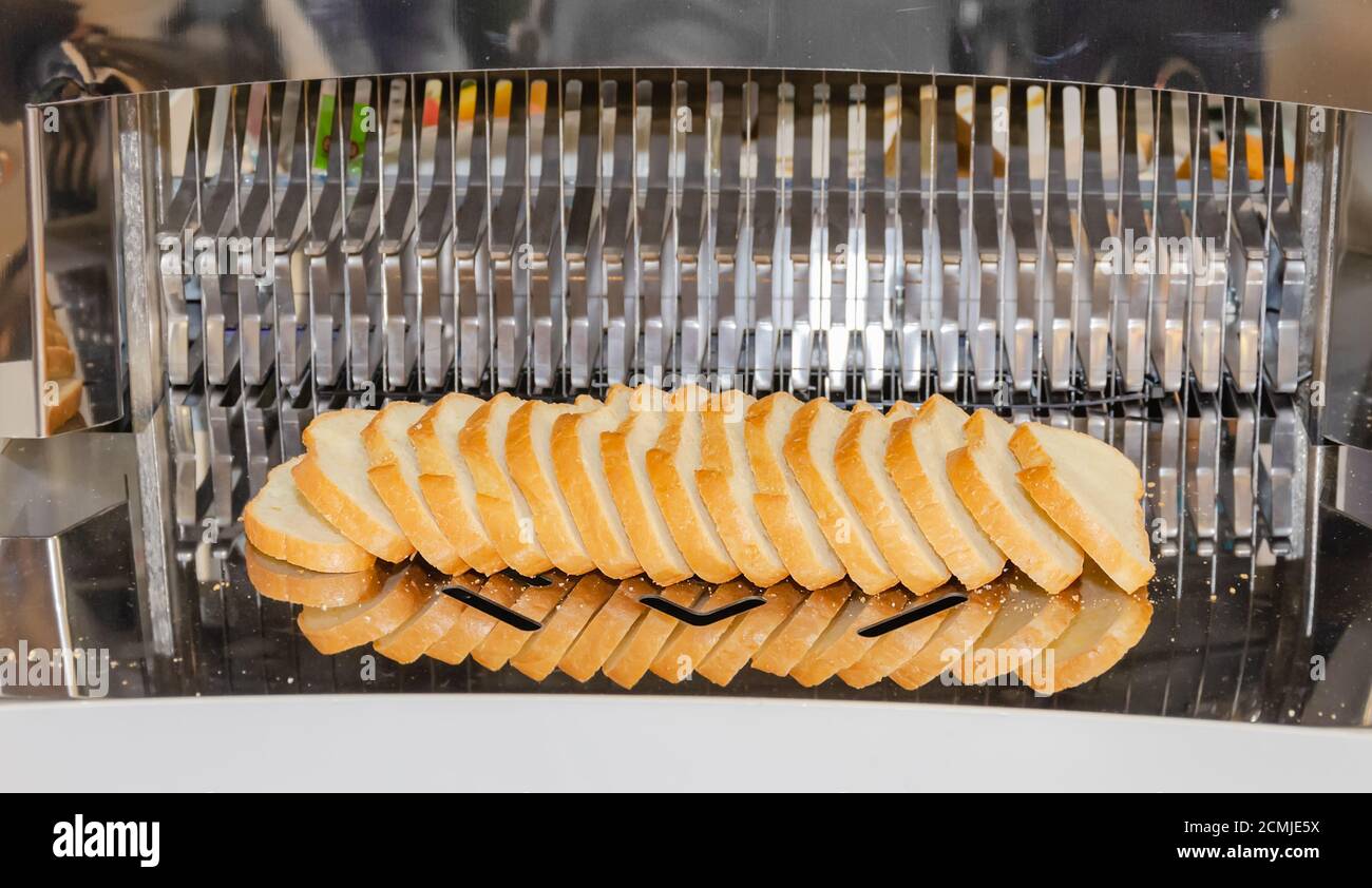 https://c8.alamy.com/comp/2CMJE5X/bread-slicing-machine-freshly-baked-loaf-sliced-close-up-2CMJE5X.jpg