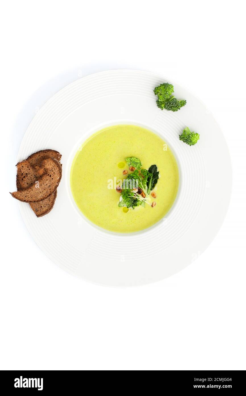 Green cream soup of broccoli and croutons close-up in a white plate. Stock Photo