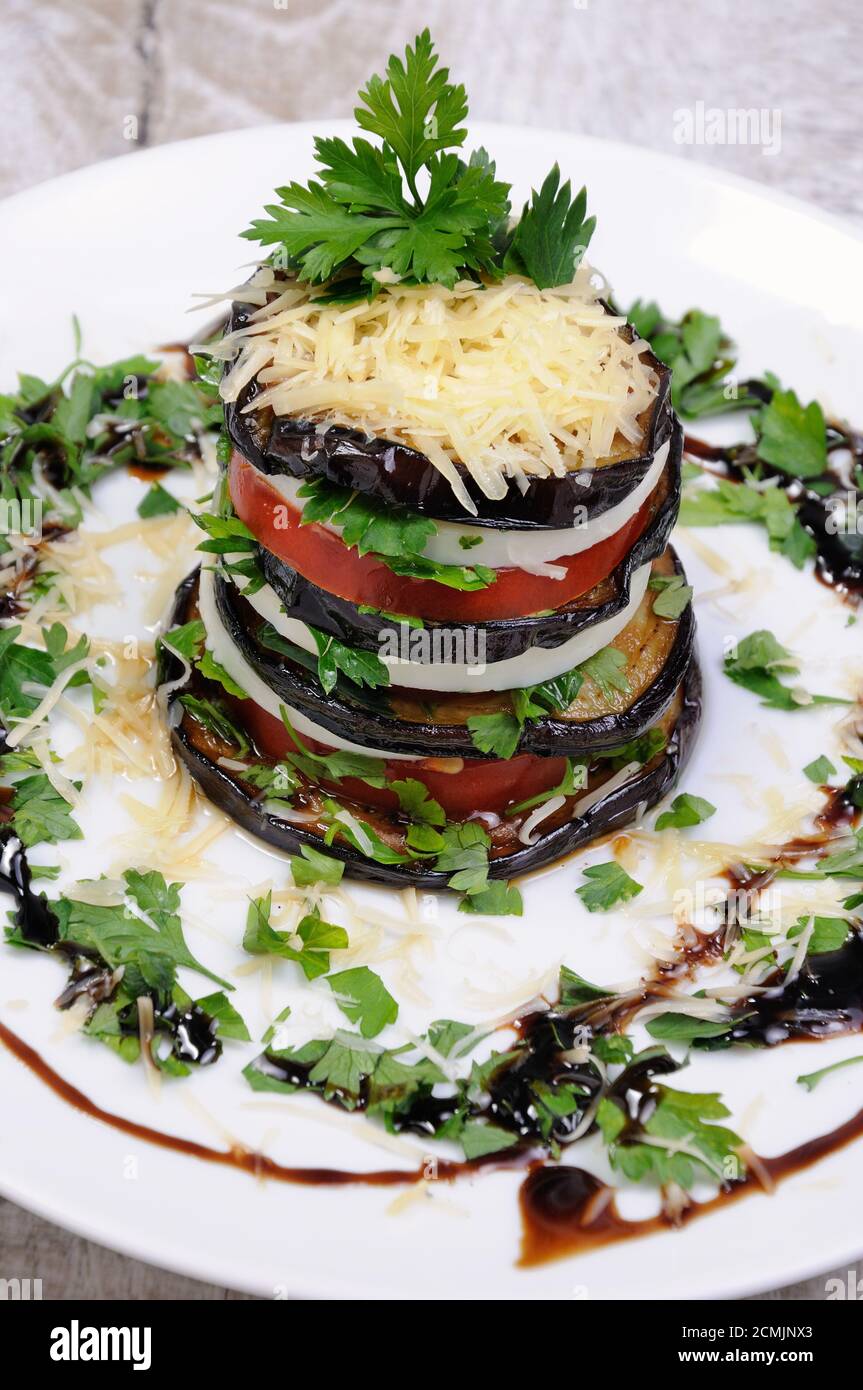 Appetizer from eggplant , slices of mozzarella combined in a pile with tomatoes spilled with