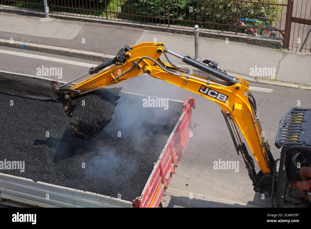 excavator picking up fresh asphalt from dumper truck Stock Photo