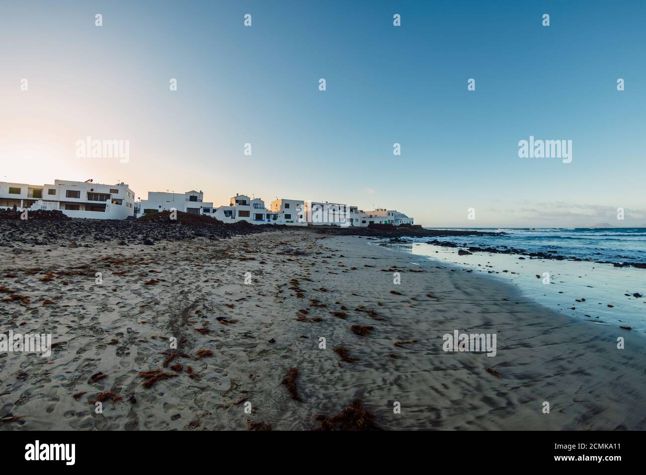 Famara beach and Caleta de Famara town with sunset tones in Lanzarote, Canary islands Stock Photo