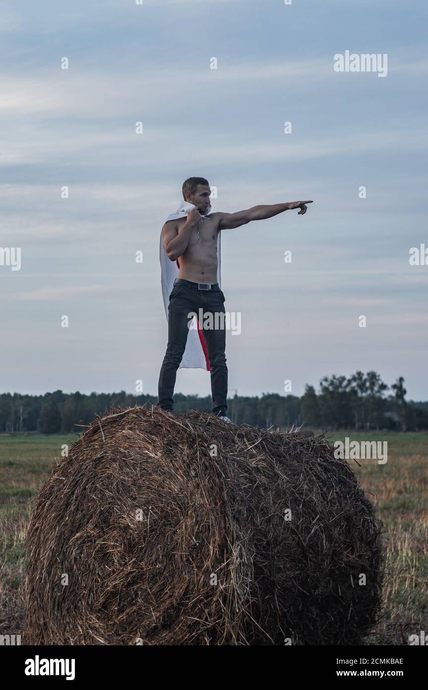 A Belarusian protester with a red and white flag behind his back points with his finger, Stock Photo