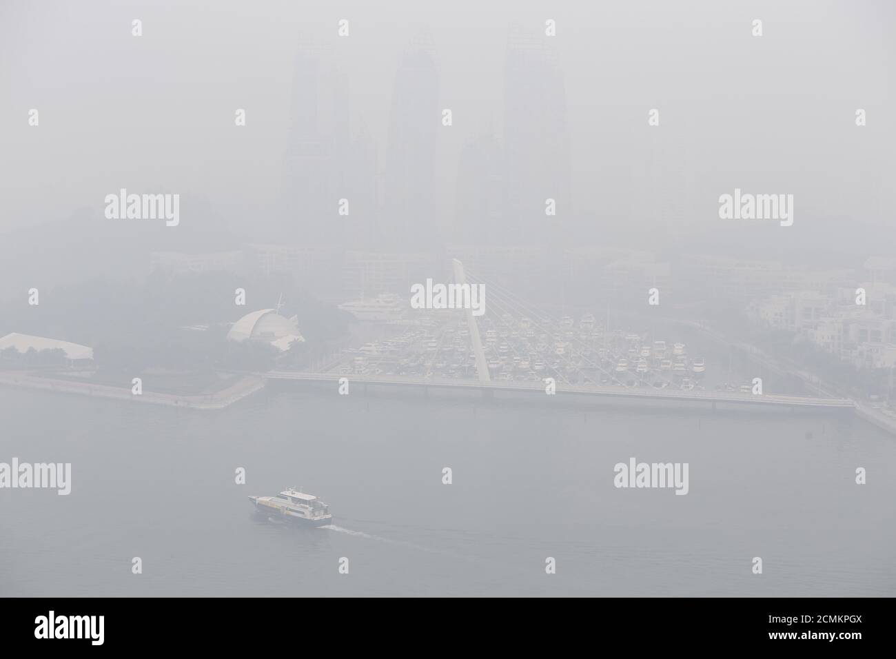 A yacht passes a marina next to a luxury condominium project shrouded by haze in Singapore September 29, 2015. The 3-hour haze Pollutant Standards Index (PSI) was at 205 at 11am on Tuesday, according to the National Environment Agency. Slash-and-burn agriculture in neighbouring Indonesia has blanketed Singapore in a choking haze for weeks. REUTERS/Edgar Su Stock Photo