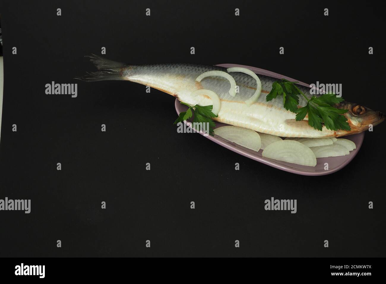 Herring is whole, undivided with onion and parsley close-up. Stock Photo