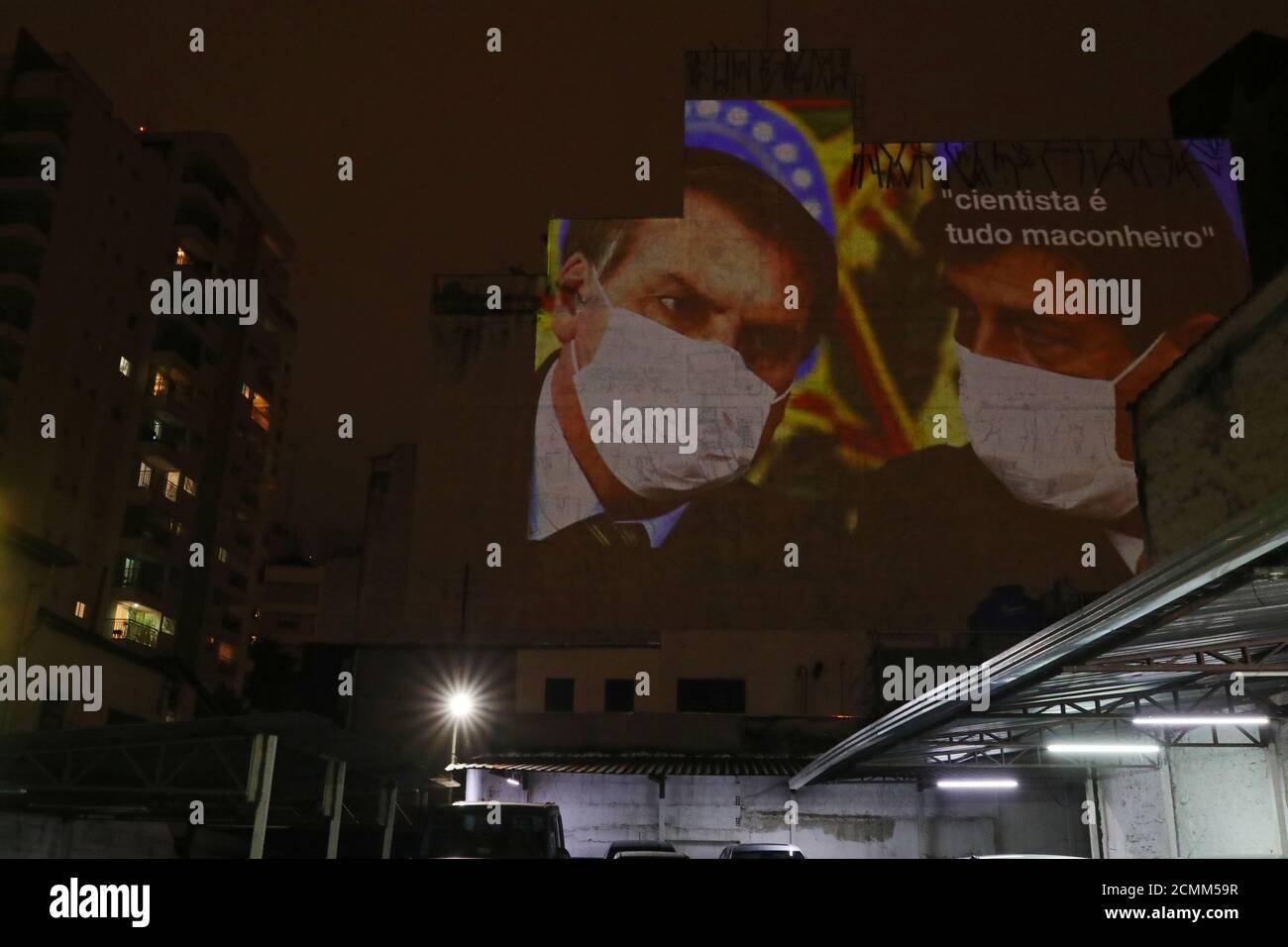 An image depicting Brazil's President Jair Bolsonaro and Health Minister Luiz Henrique Mandetta wearing protective face masks and the phrase “Scientists are all potheads” is projected on the wall of a building as a protest, following the coronavirus disease (COVID-19) outbreak in Sao Paulo, Brazil, March 19, 2020. REUTERS/Amanda Perobelli Stock Photo