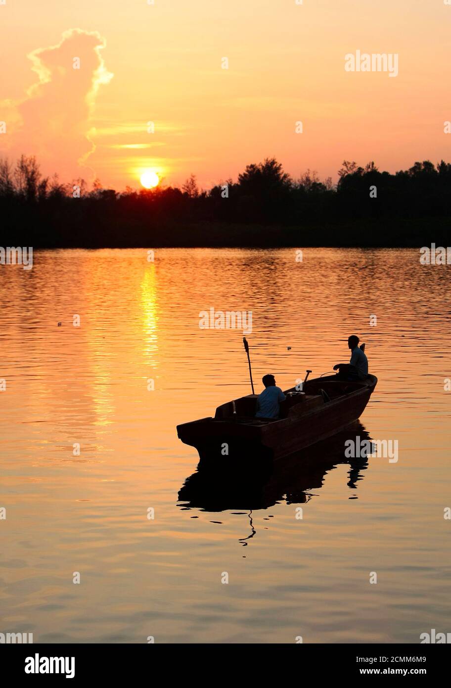 Two people set out in a boat at sunrise in the port of Kijang on the Indonesian island of Bintan October 26, 2009. REUTERS/Vivek Prakash (INDONESIA SOCIETY) Stock Photo