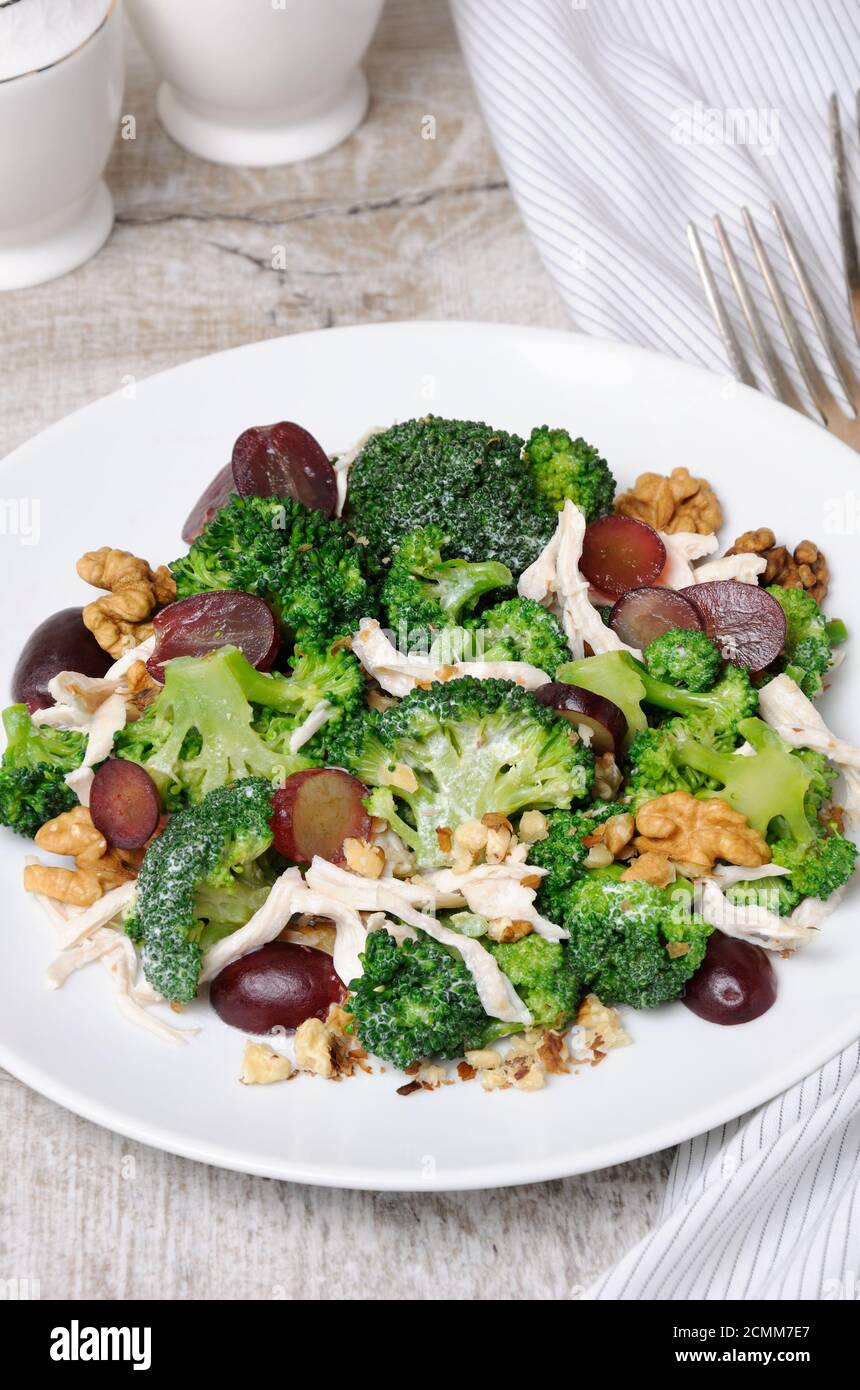 Dietary broccoli salad with chicken, sliced grapes, crushed nuts and yoghurt dressing Stock Photo