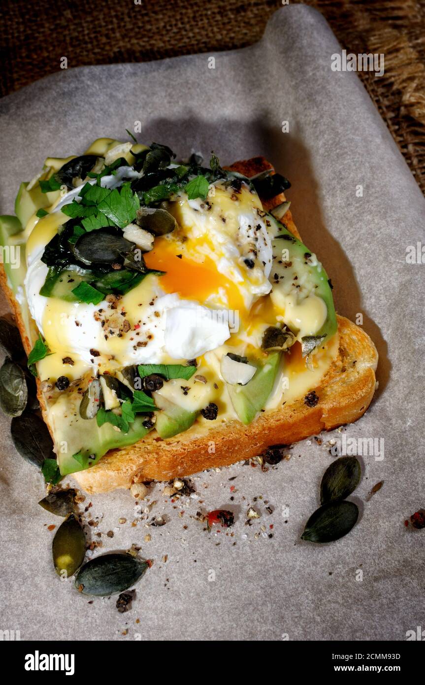 Eggs Benedict on toast with Dutch sauce, slices of avocado Stock Photo