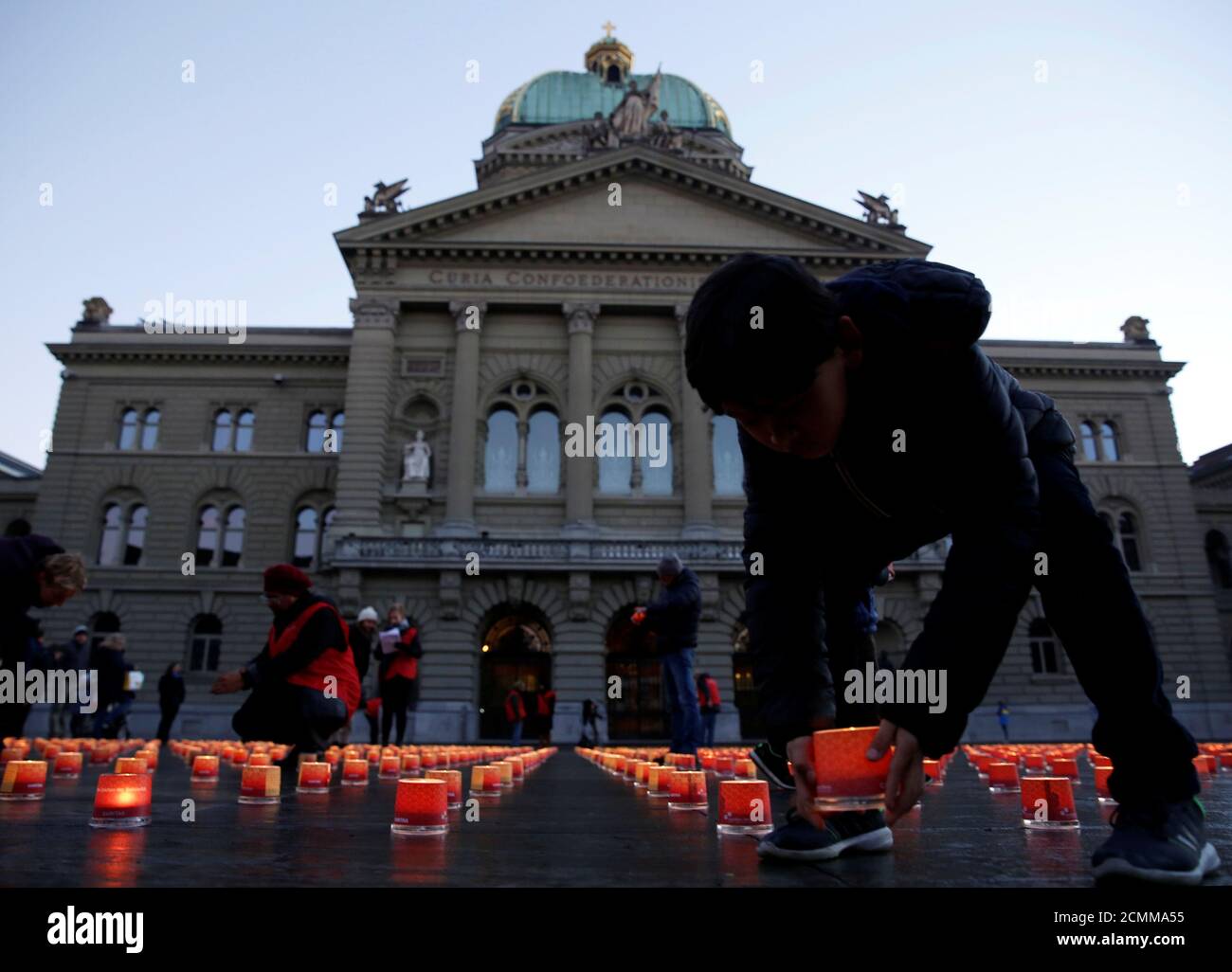 People place candles during the "One Million Candles" event by Swiss