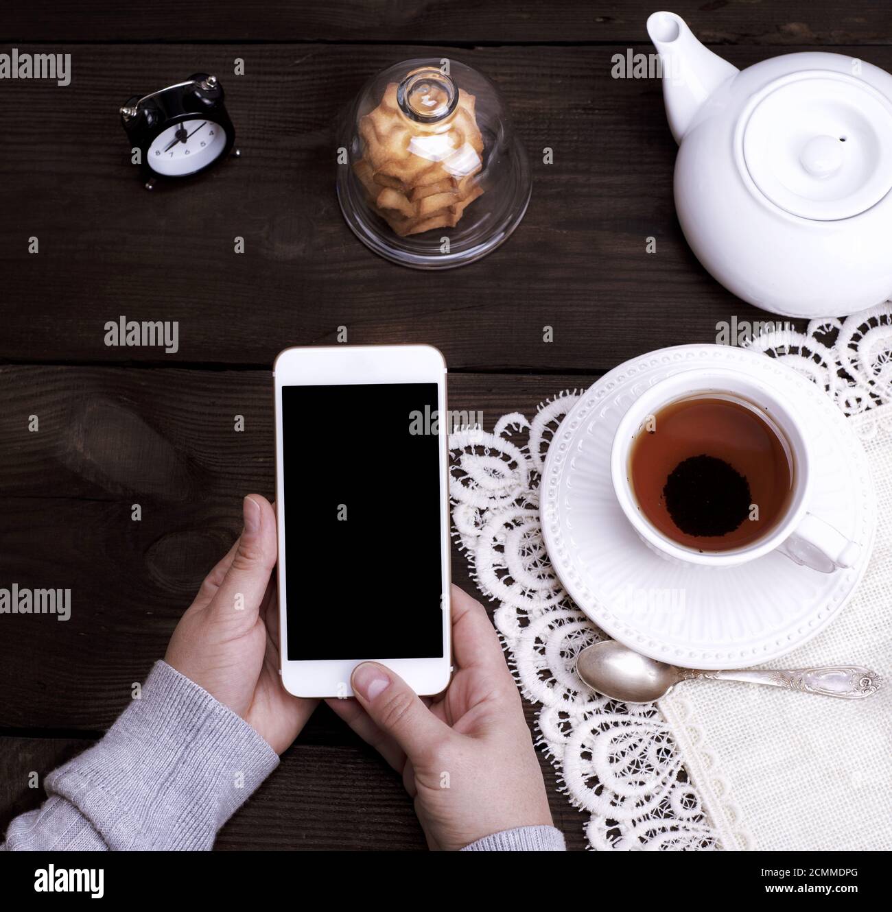 two female hands holding a white smartphone with an empty black screen Stock Photo