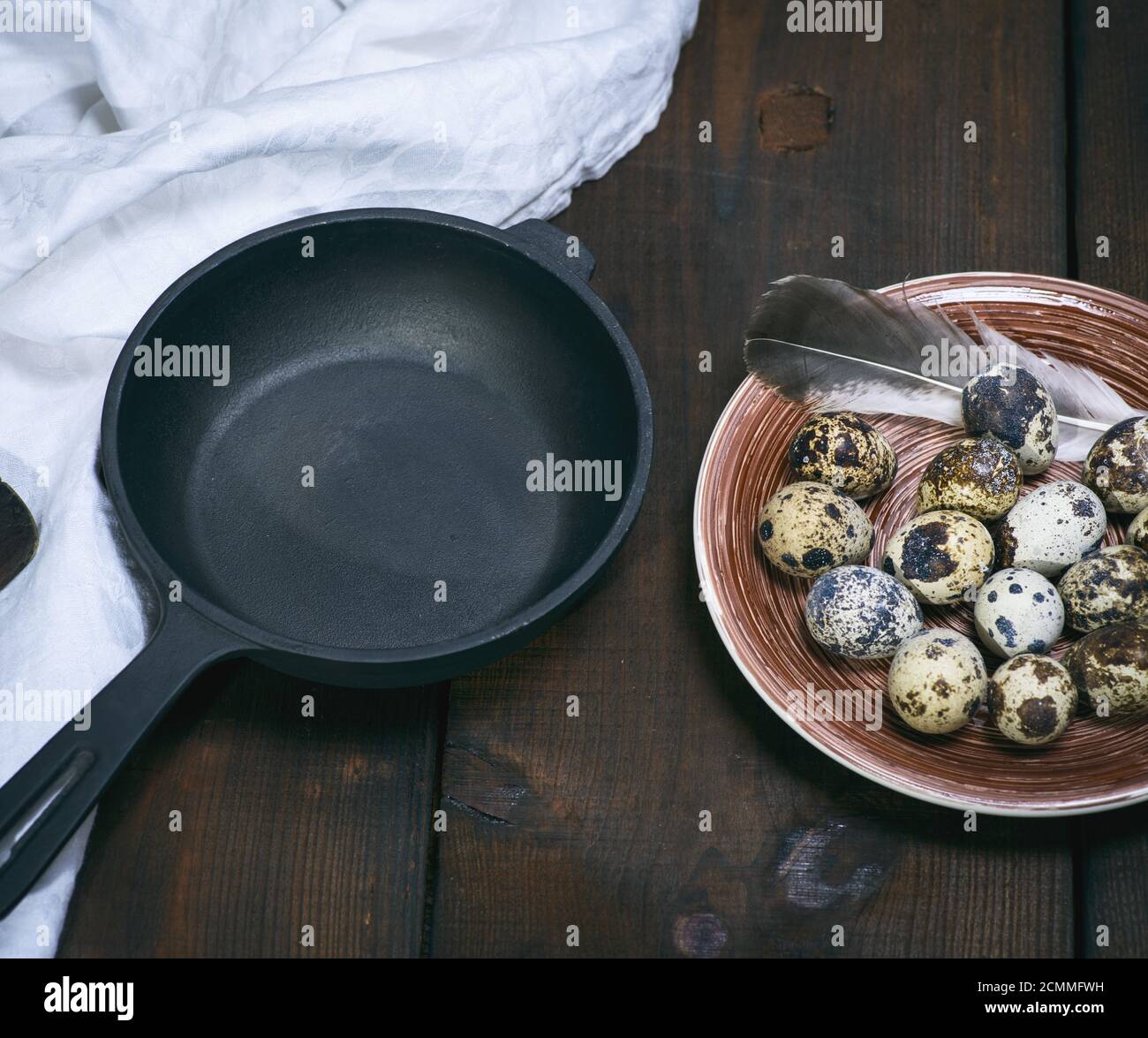 empty round cast-iron frying pan and raw quail eggs in a plate Stock Photo