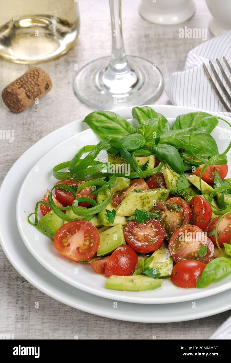 Delicate slices of avocado with tomatoes, dressed   pesto sauce. Stock Photo