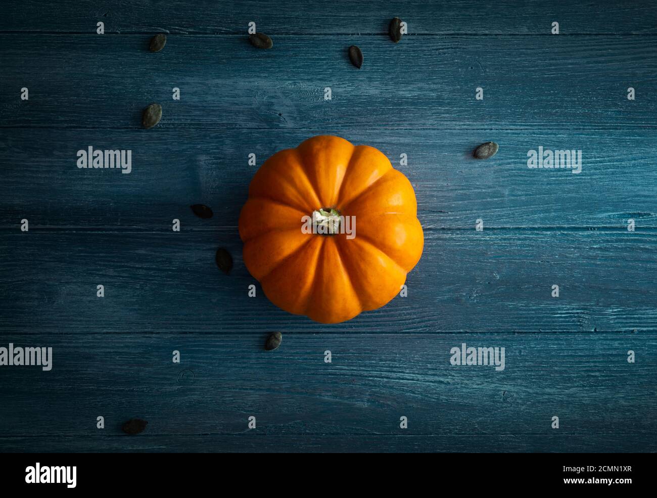 Orange pumpkin on blue wooden background top view, ideal for backgrounds, layouts and Template Stock Photo