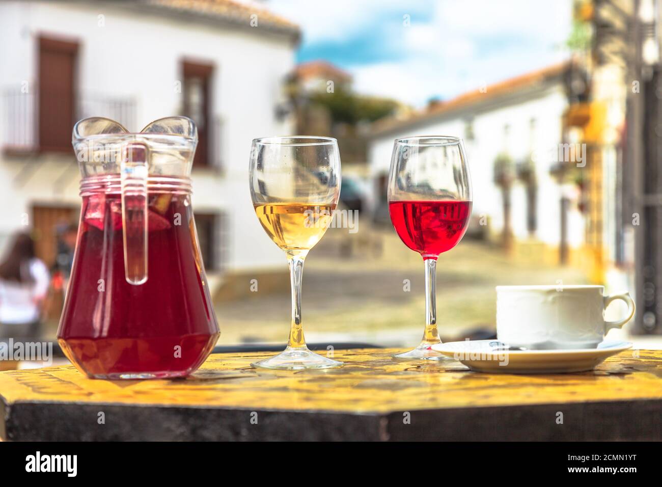 https://c8.alamy.com/comp/2CMN1YT/pitcher-of-sangria-with-coffee-cup-and-red-and-white-glasses-of-wine-on-a-blurred-spanish-countryside-background-in-spain-2CMN1YT.jpg