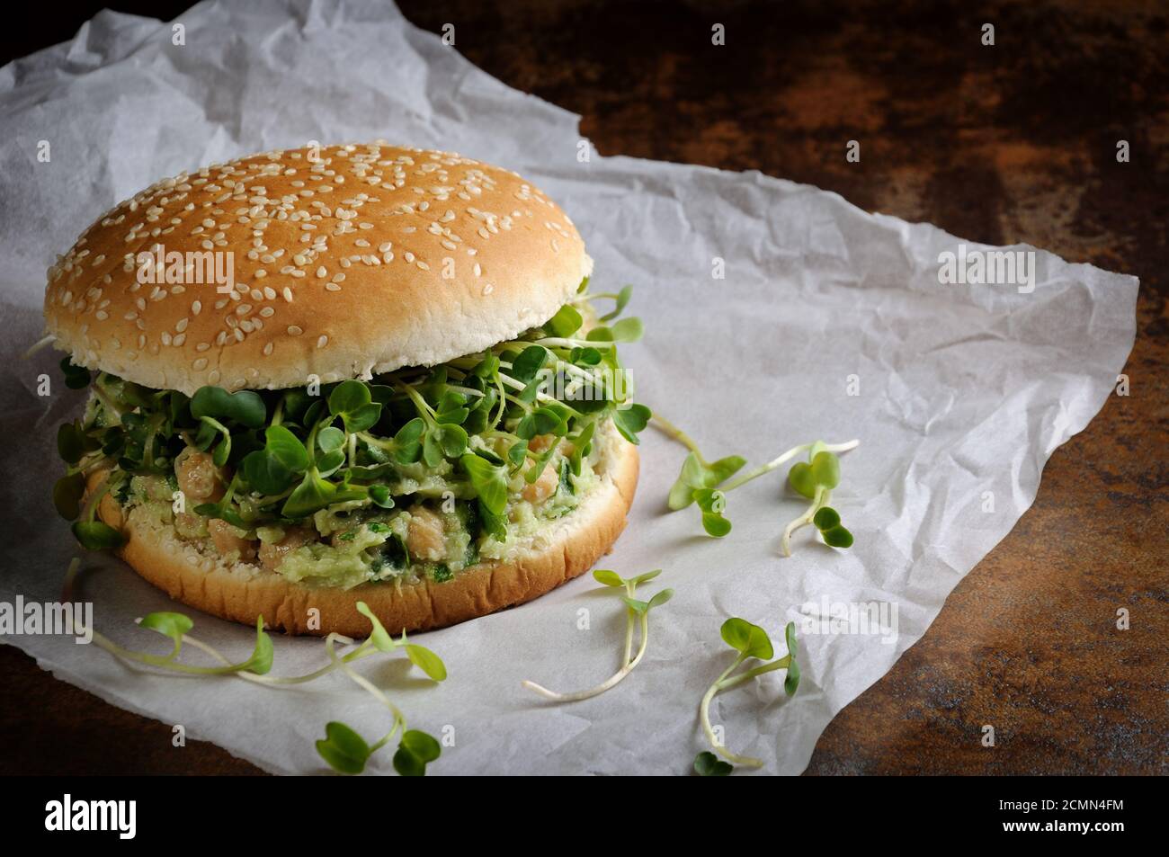 A vegetarian burger made from a gluten-free bun with chickpeas, avocado and herbs, radish sprouts. Stock Photo