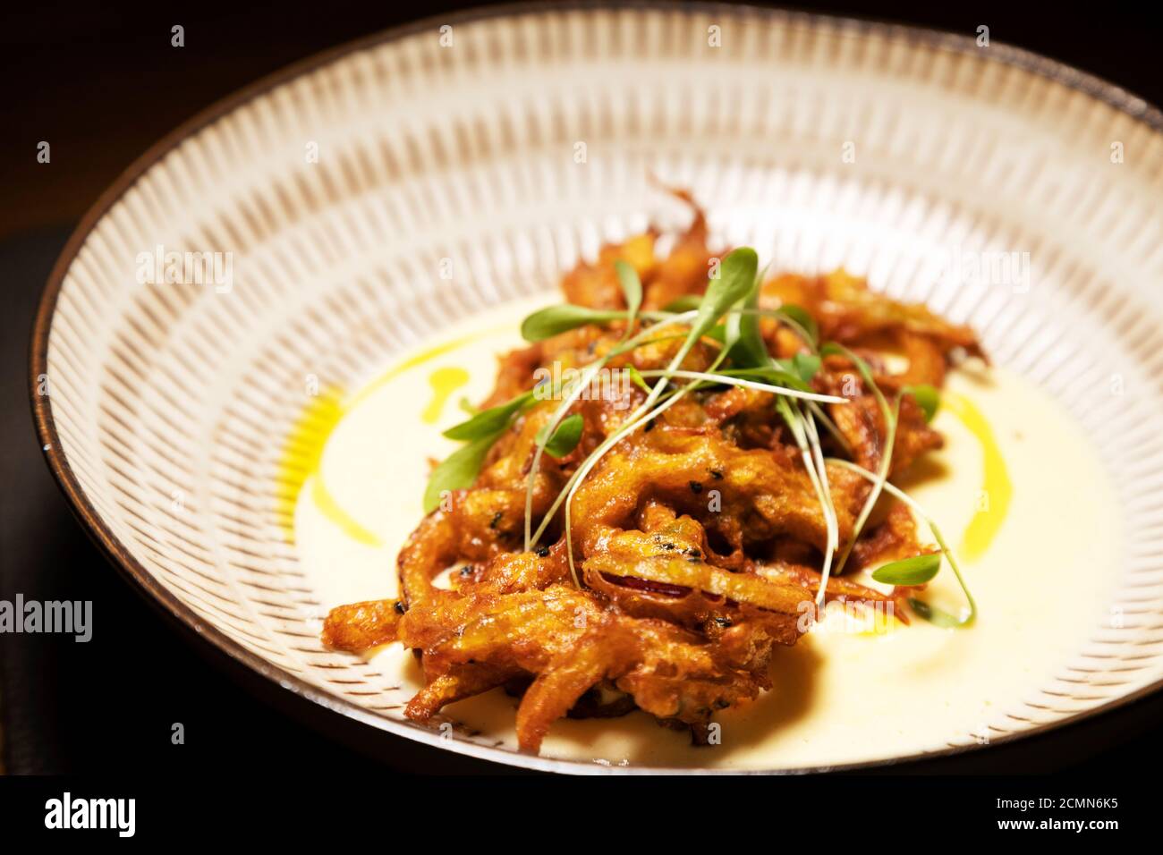 Onion bhaji made with spring onion. The bhaji is served with a smoked cheese sauce. Stock Photo